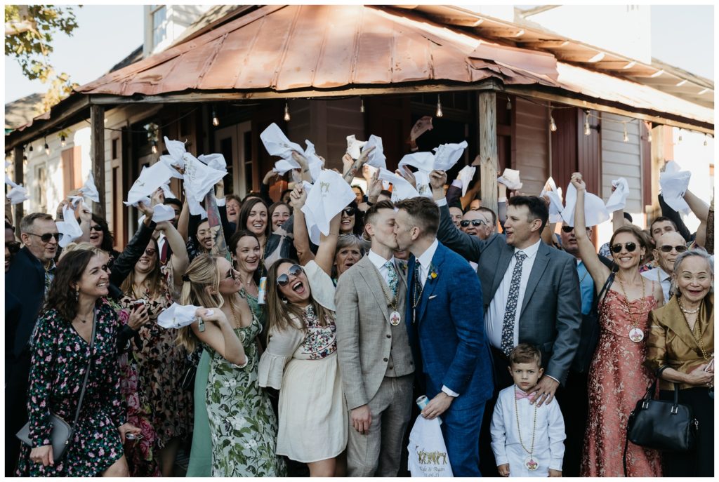 Guests wave handkerchiefs as the couple kisses outside the Tigermen Den wedding