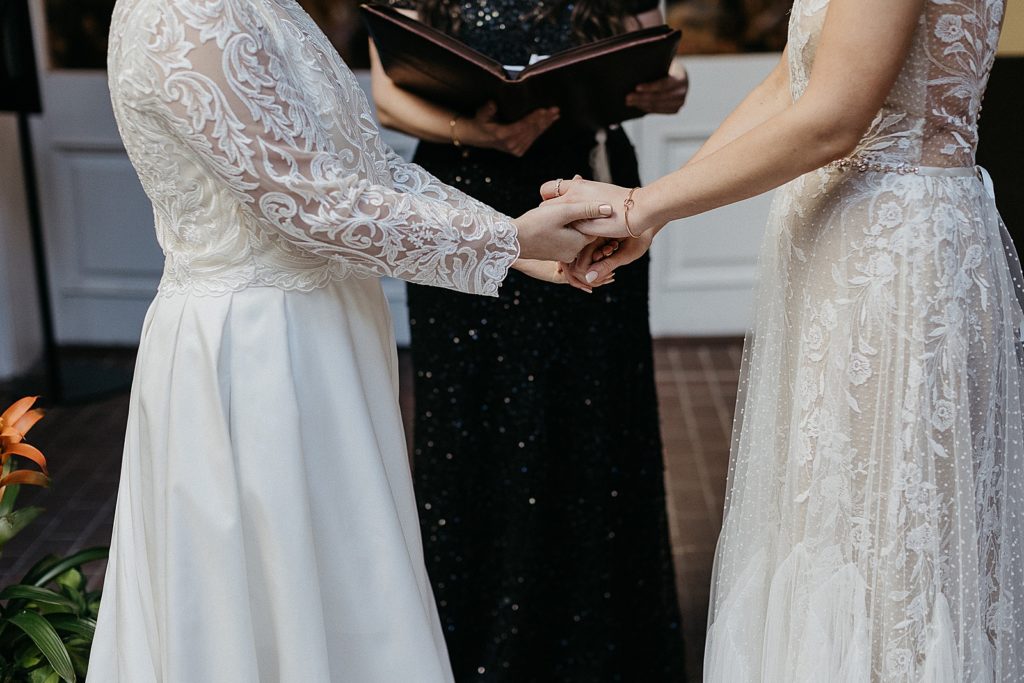 Two women hold hands during a French Quarter wedding ceremony