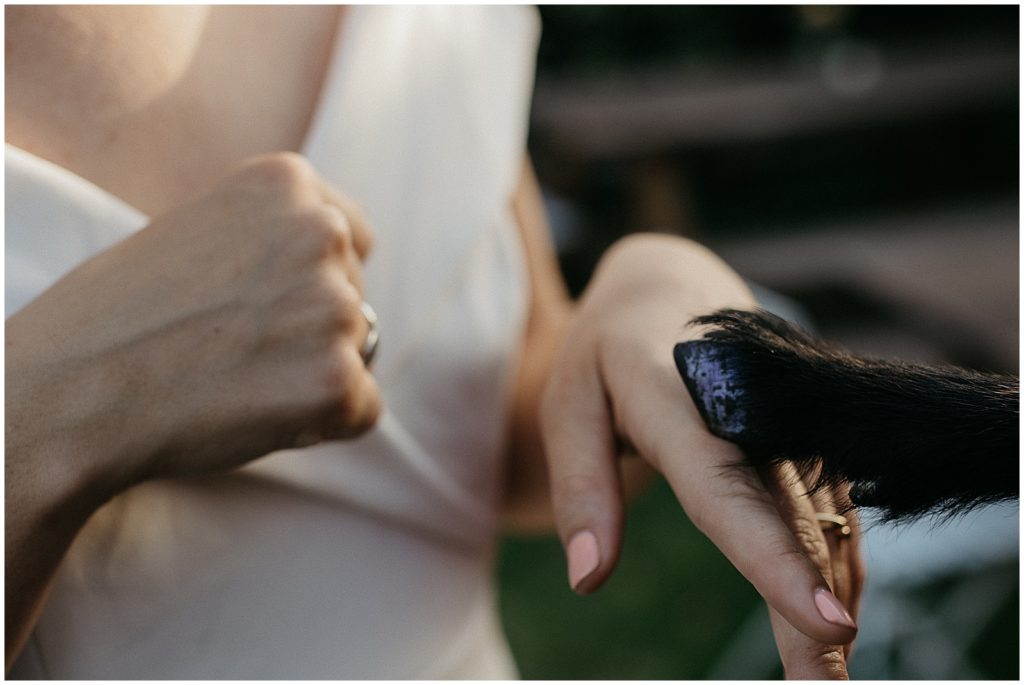 A goat's hoof rests on a bride's hand.