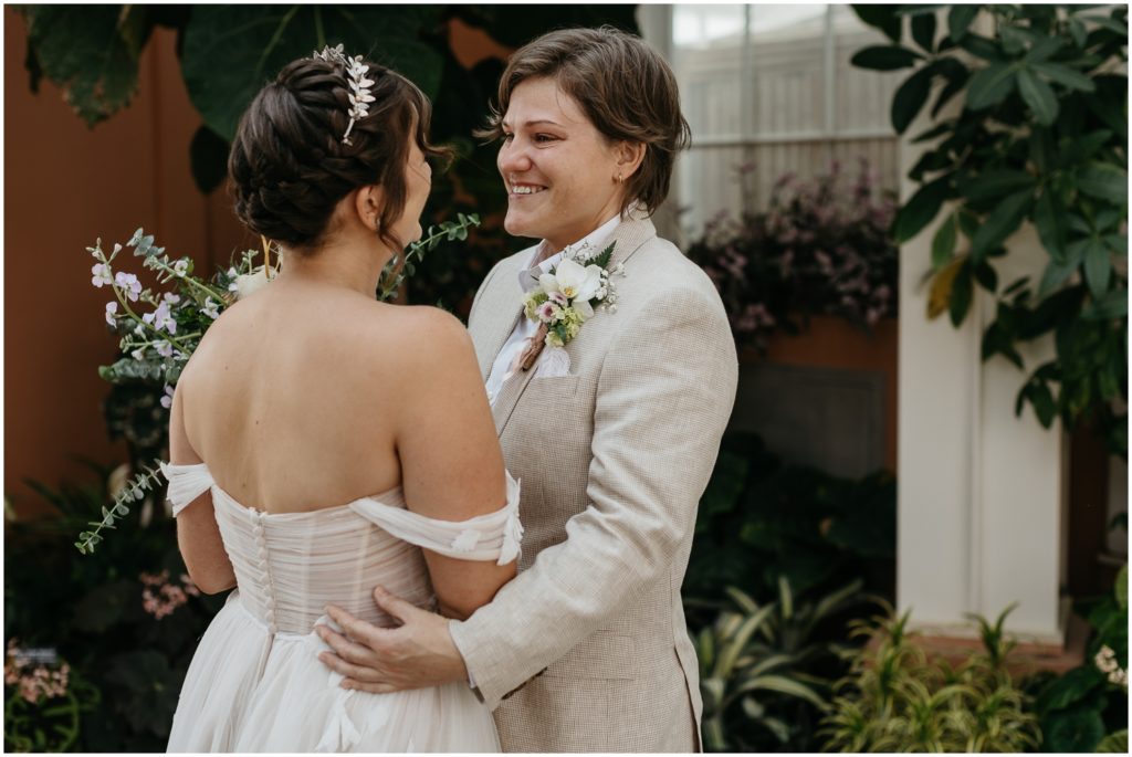 Em puts their hands on Britt's waist at their New Orleans Botanical Garden wedding.