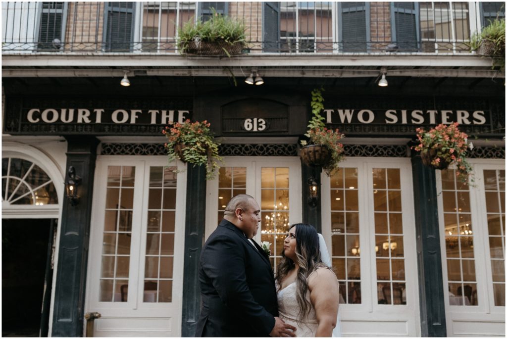 A man and woman embrace in front of The Court of Two Sisters at their New Orleans micro wedding.