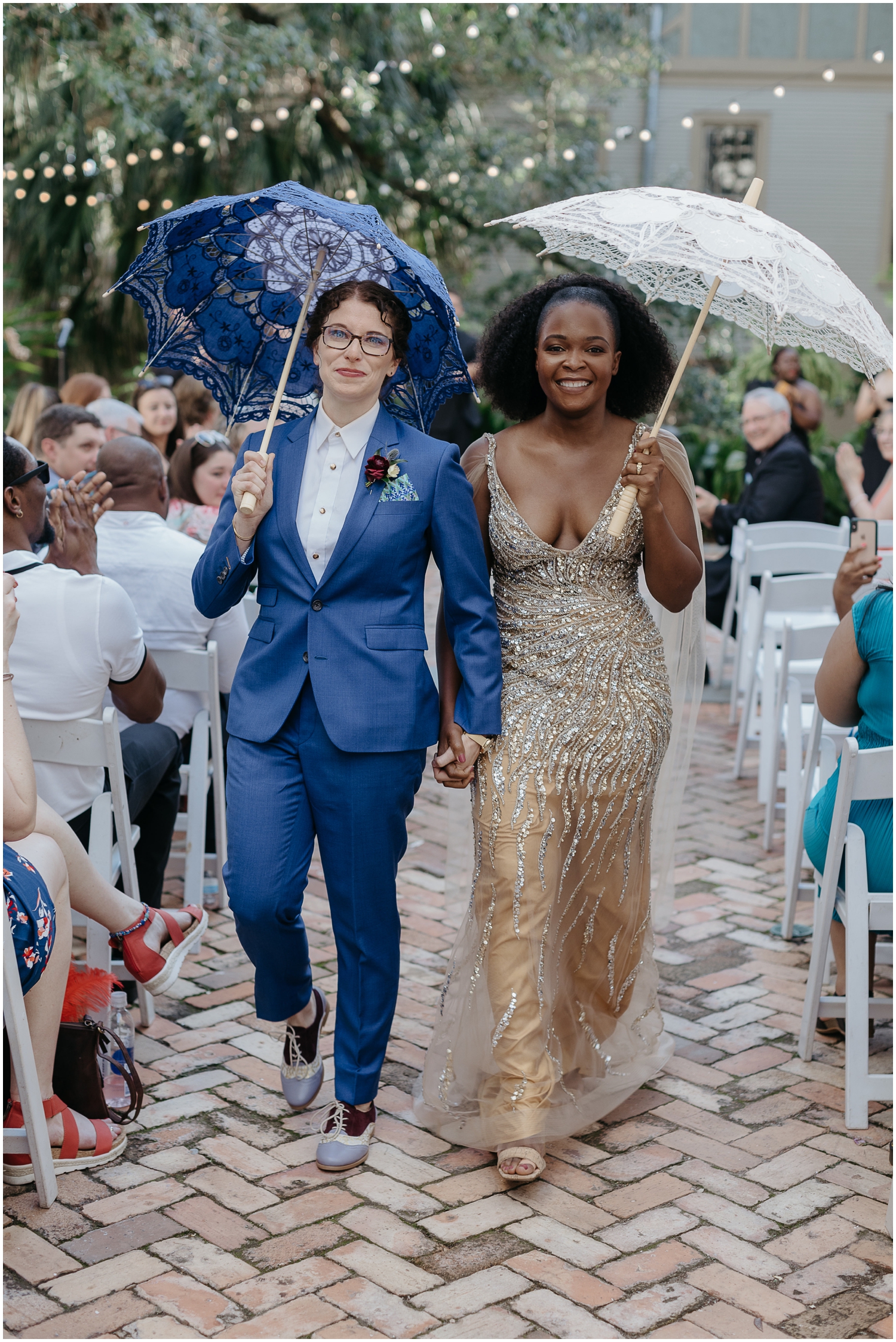 A couple walks down the aisle with wedding umbrellas at their Degas House wedding.