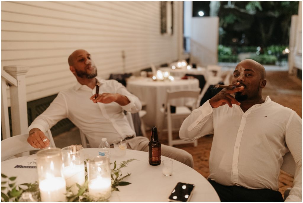 Wedding guests smoke cigars at a table.