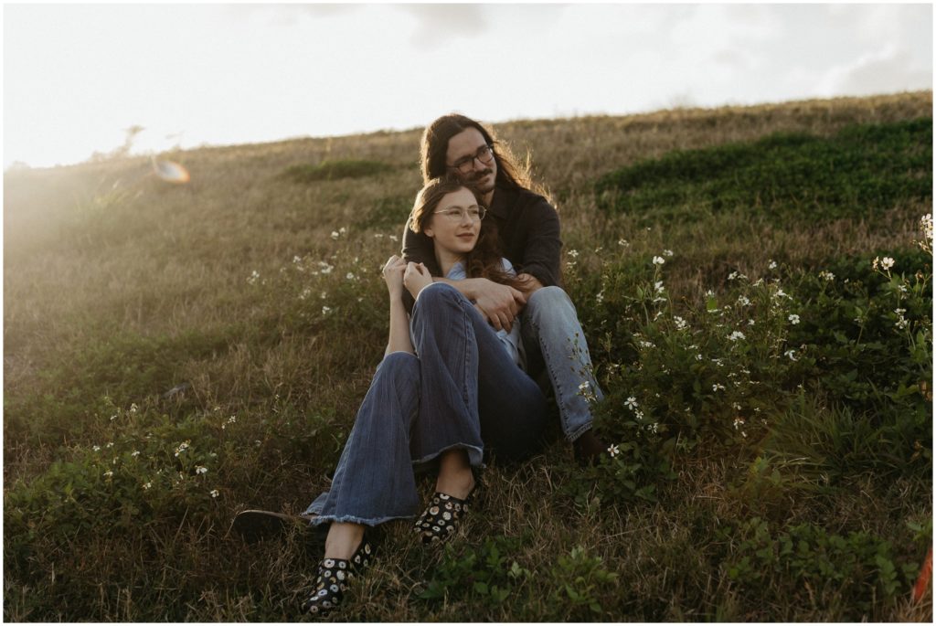 A couple sits in a wildflower field for New Orleans engagement photos.