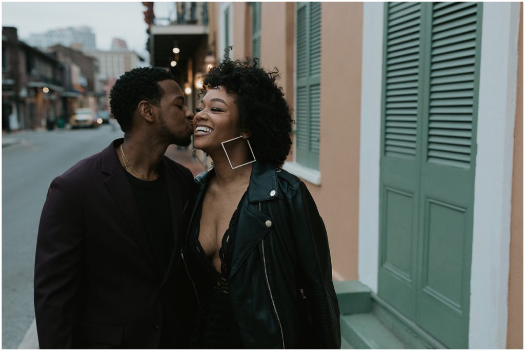 A man kisses a woman on the cheek at a New Orleans engagement photo location.