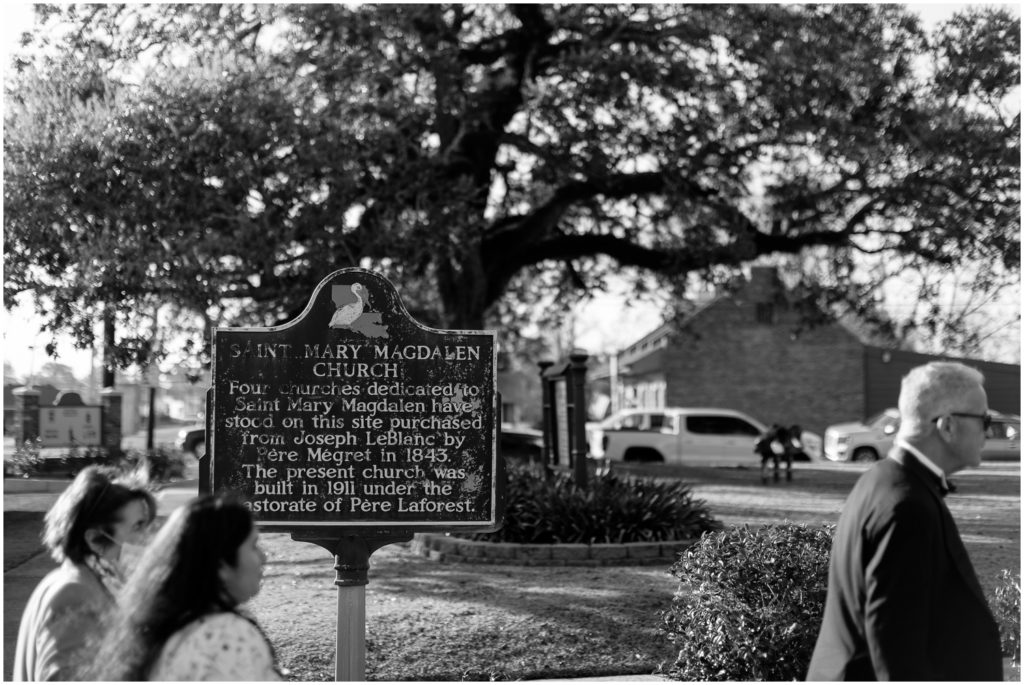 Wedding guests walk past a historical marker outside the wedding church.