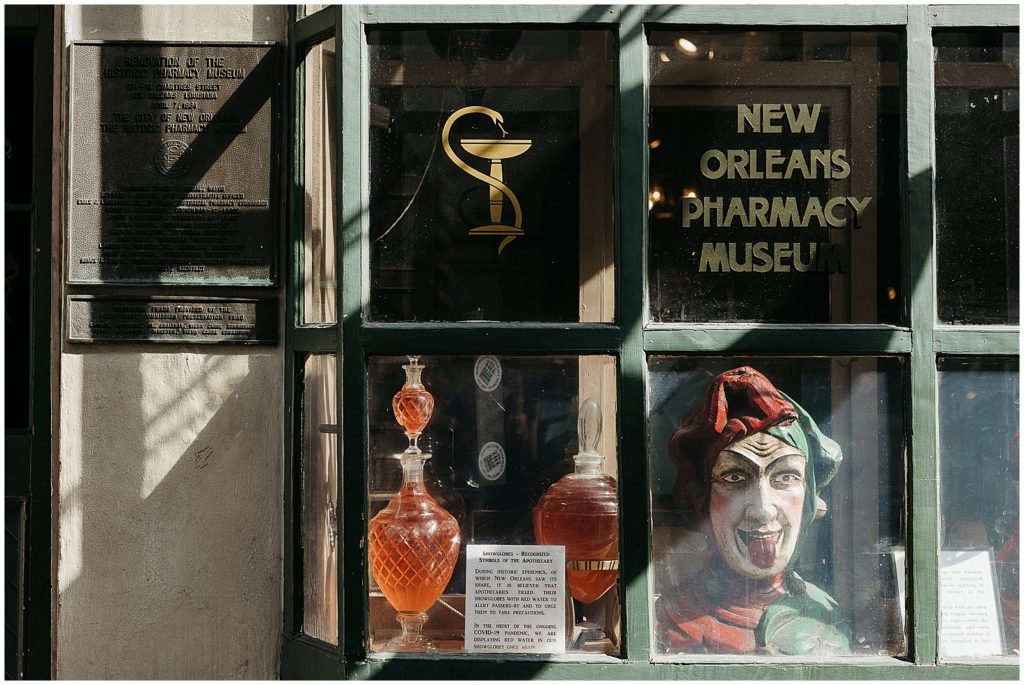 An antique Mardi Gras mask sits in the window of the Pharmacy Museum.