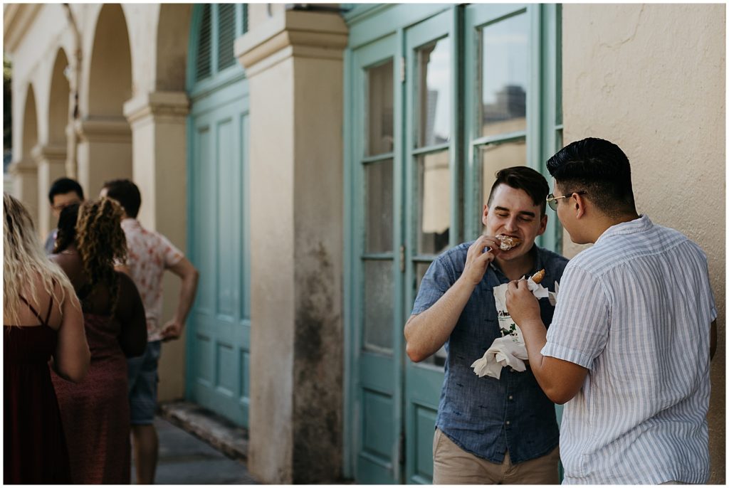 A couple eats beignets to celebrate their French Quarter engagement photos.