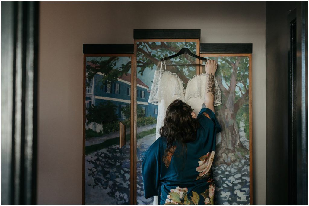 A woman takes her wedding dress off a painted dresser for her New Orleans destination wedding.