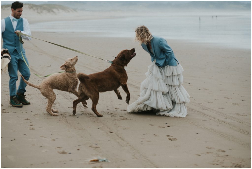 Holly bends forward to greet her dogs on the Oregon beach.