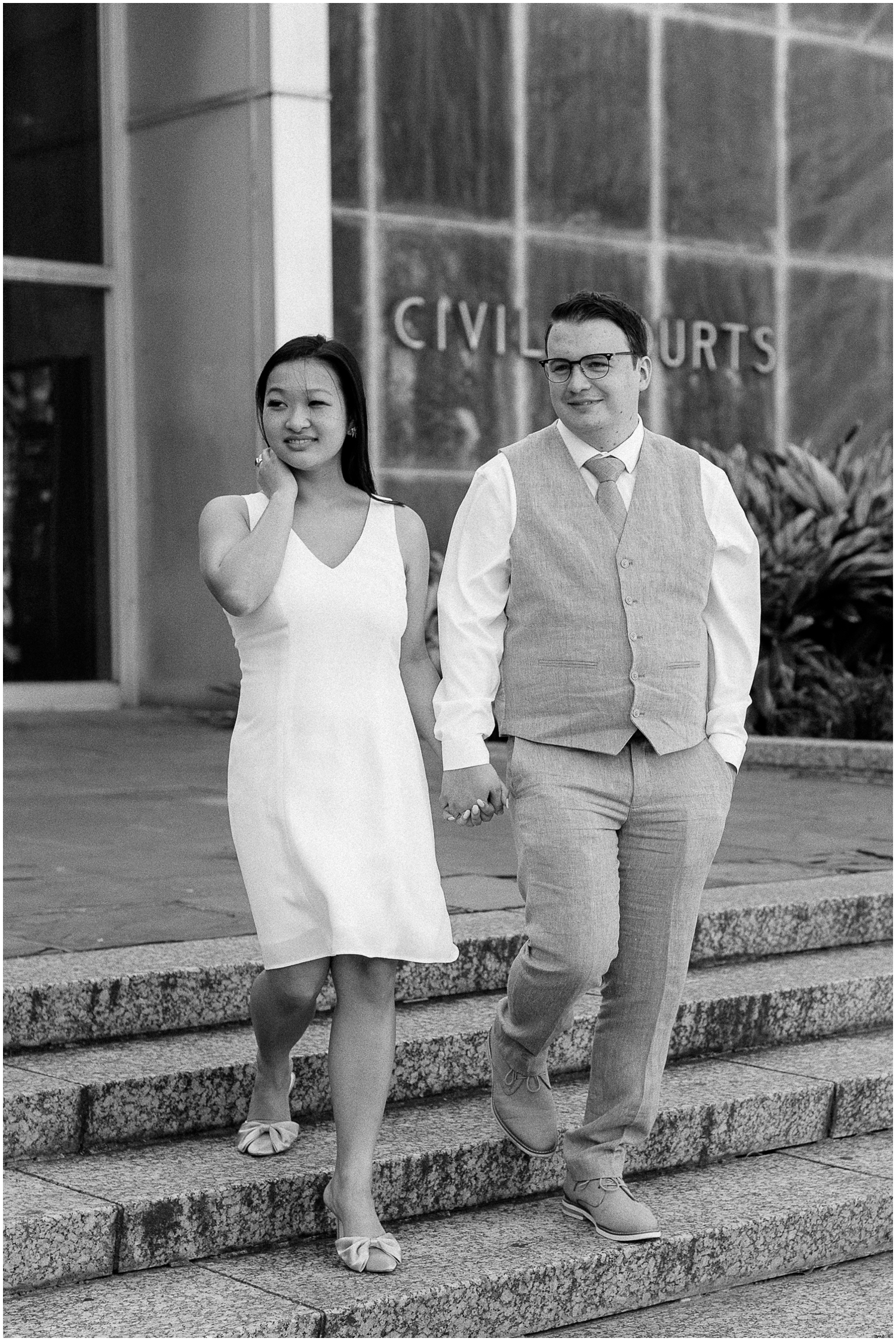 A couple holds hands and walks down the steps after their New Orleans courthouse wedding.