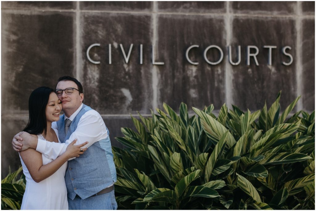 A couple embraces in front of the City Courts sign.