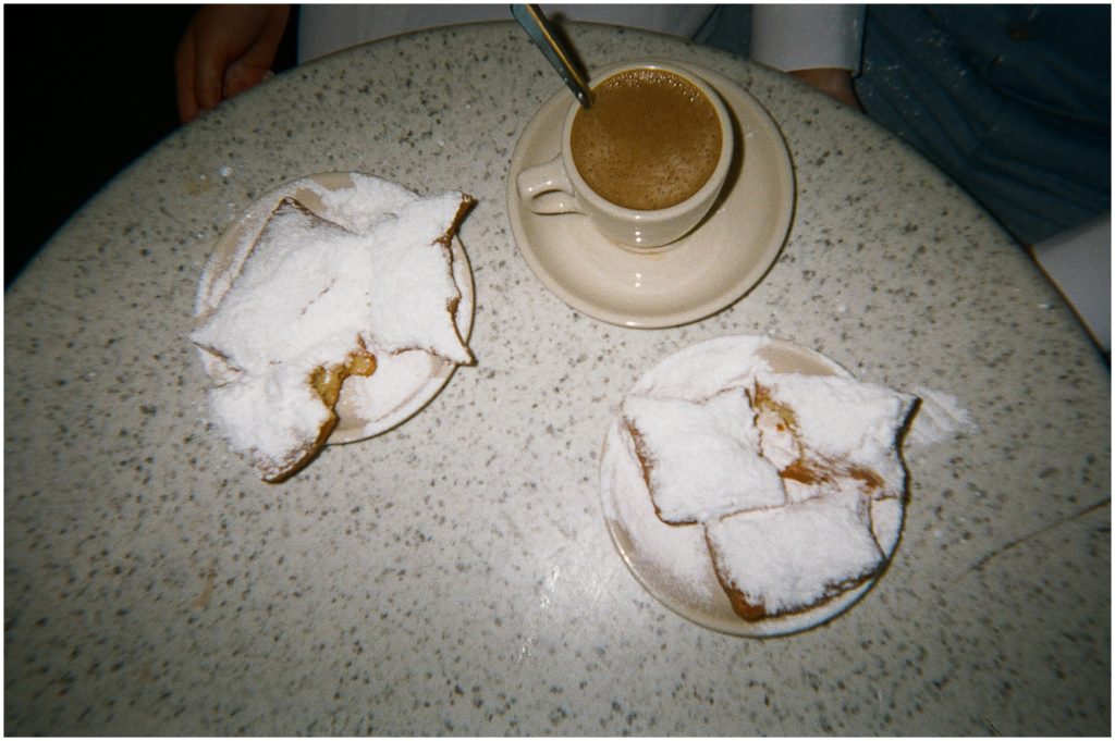 Plates of beignets sit around a cup of coffee.