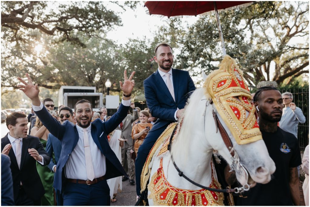 A groom rides a horse towards an Indian wedding ceremony.