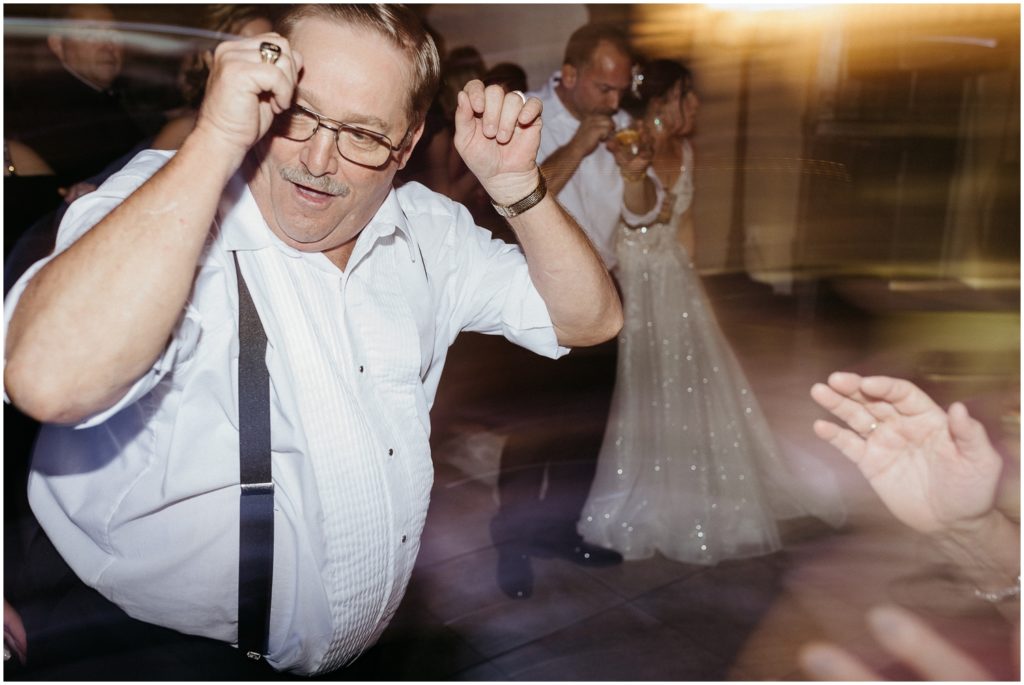 A wedding guest raises his arms and dances.