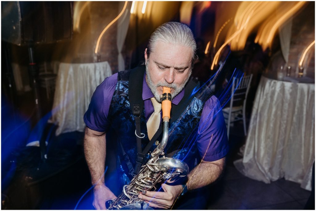 A man leans forward playing a saxophone.