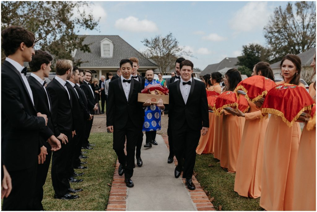 Groomsmen walk past bridesmaids in peach dresses on their way to an event on the weekend wedding itinerary.