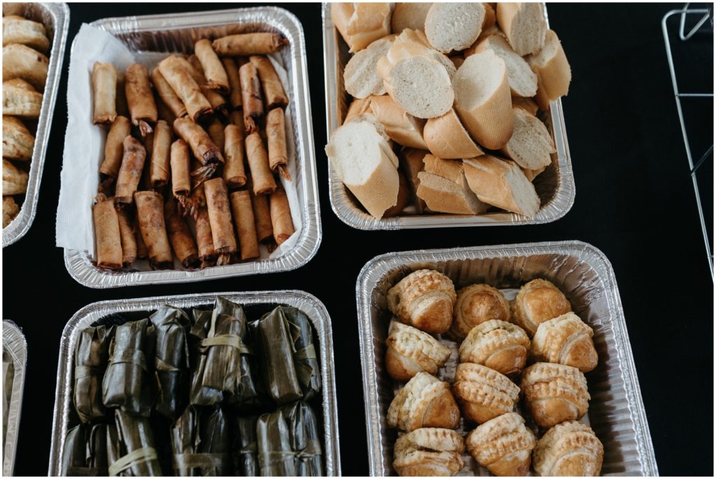Spring rolls and pastries sit in foil pans for wedding guests.