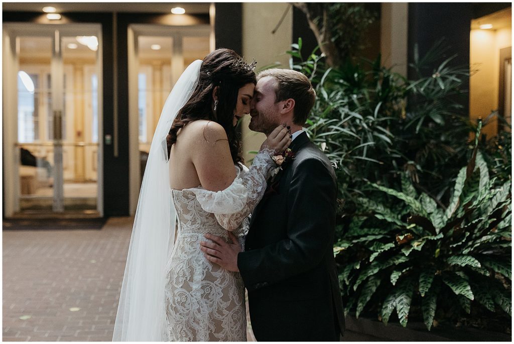 A bride and groom press their foreheads together in a French Quarter courtyard.
