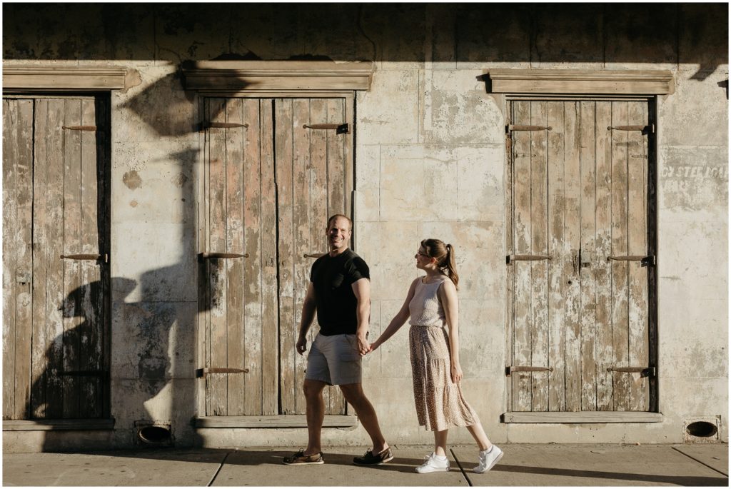 Eric holds Lauren's hand as they walk past a historic cottage during their honeymoon photoshoot.