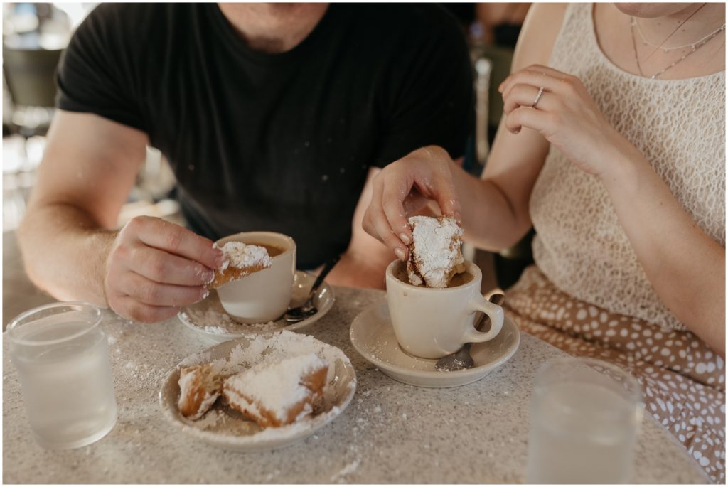 Powdered sugar flies around as the couple eats beignets.