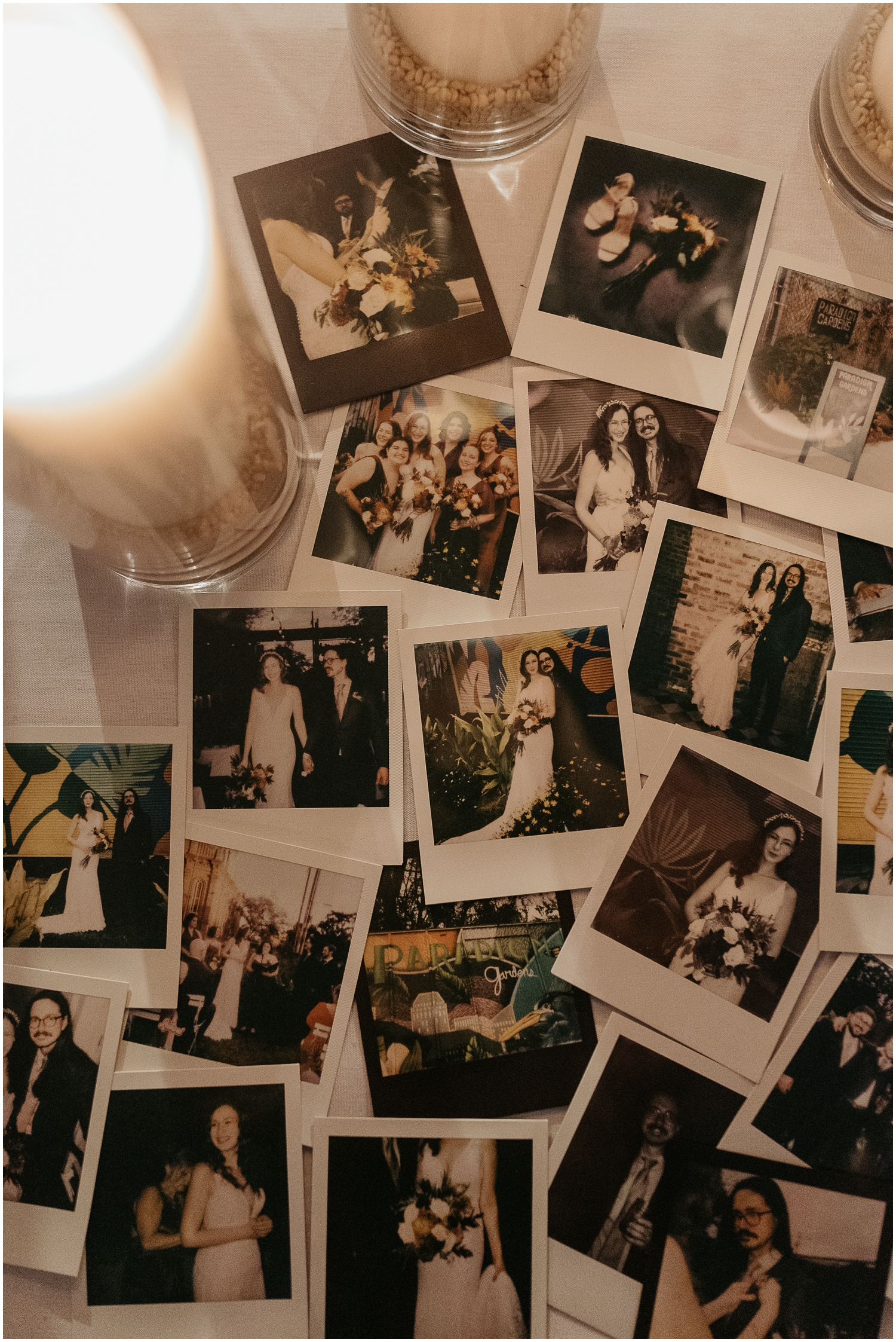 Polaroid wedding photos are arranged around candles on a white table.