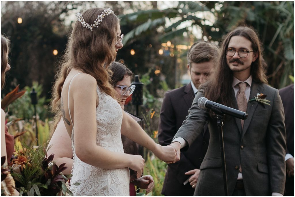 Jared and Penny hold hands during their winter garden wedding ceremony.