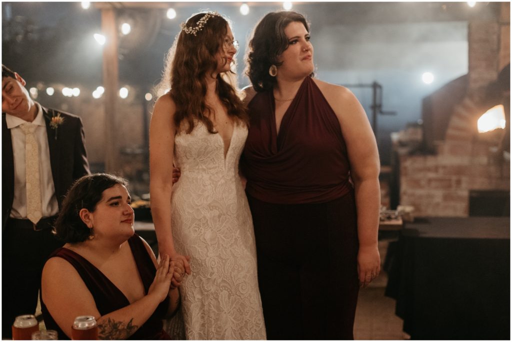 A bride stands with her bridesmaids and listens to speeches.