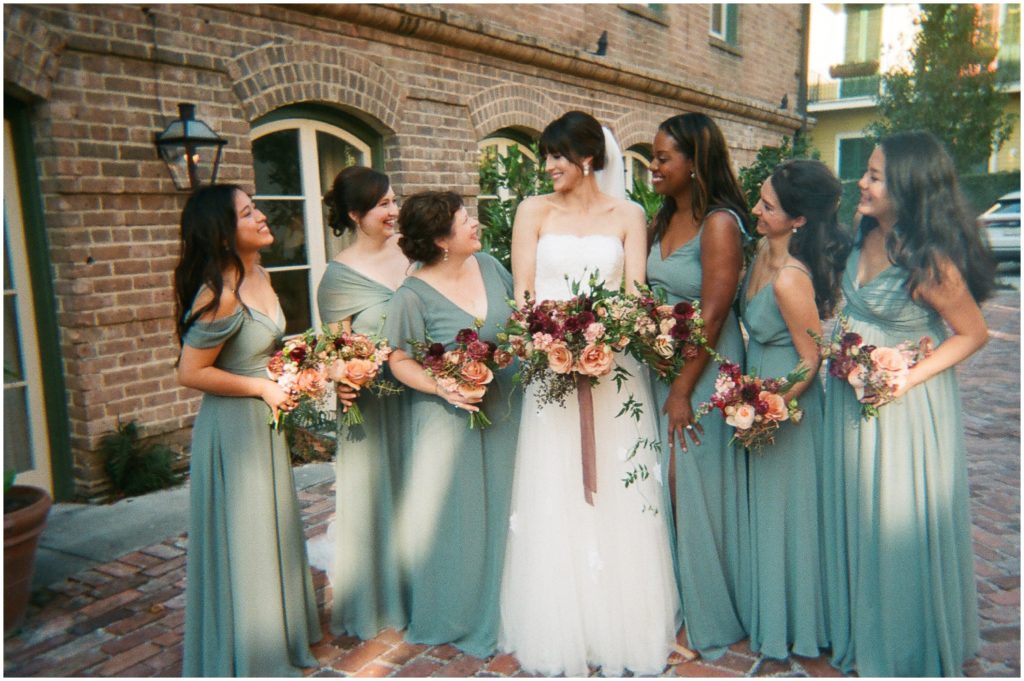 A bride stands surrounded by her bridesmaids in blue dresses in an image taken on disposable cameras for weddings.