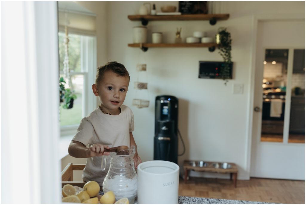 A child stirs a pitcher of lemonade in his family's kitchen.