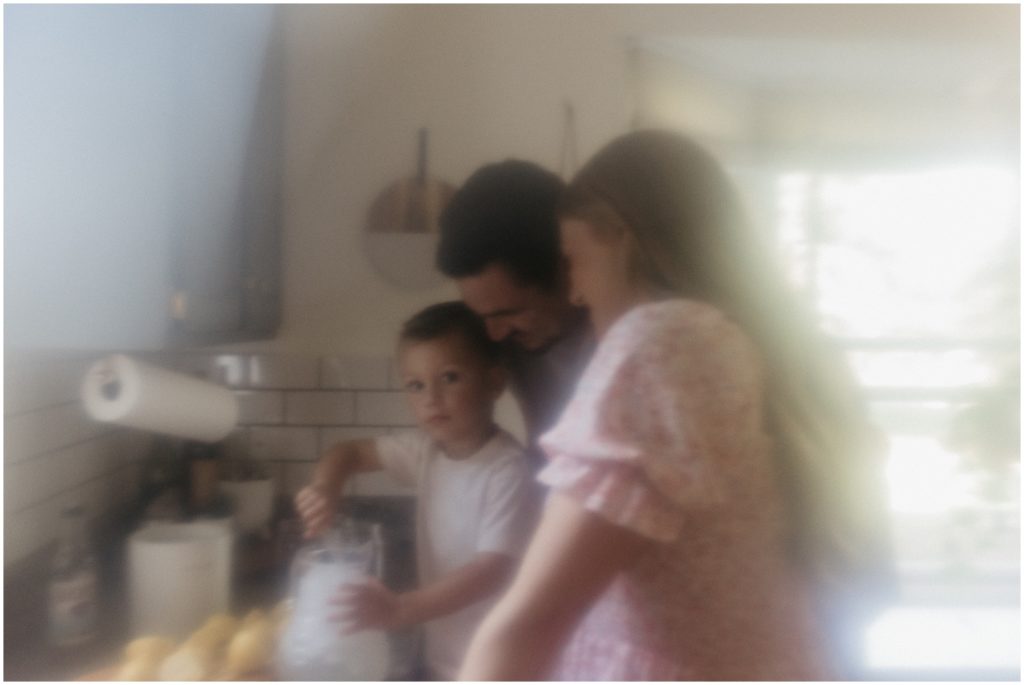 A family crowds around a kitchen counter during a maternity session.