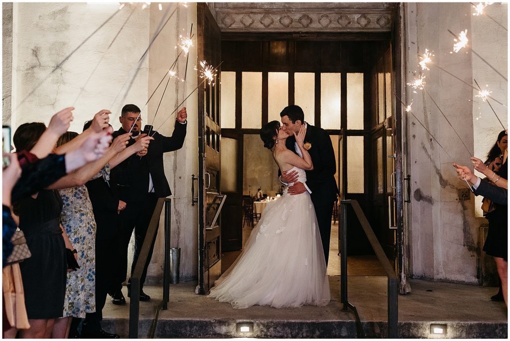 A bride and groom kiss at the start of their sparkler exit from their New Orleans wedding.