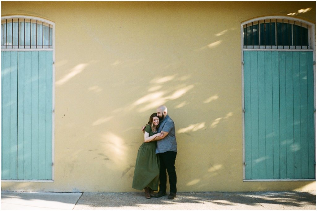Omar and Anastasia embrace beside a yellow building in New Orleans.