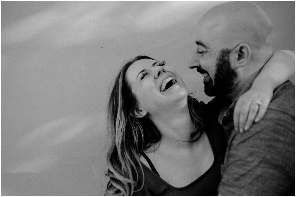 A woman throws her arm around a man's neck laughing in a New Orleans engagement photo.